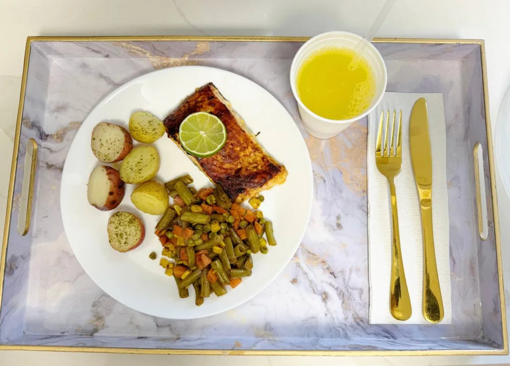Plato saludable con salmón a la plancha, papas y vegetales servido en Charm Home Miami durante recuperación postoperatoria de BBL.